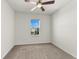 Carpeted bedroom with a ceiling fan and a window overlooking the neighborhood at 3214 Painted Blossom Ct, Lutz, FL 33558