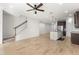 Open-concept living space with wood floors, stairs and kitchen island with a stainless steel sink at 3214 Painted Blossom Ct, Lutz, FL 33558