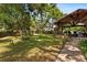 Lush backyard with a covered patio area featuring a stone fireplace, seating, and well-maintained landscaping for relaxation at 4508 Compass Oaks Dr, Valrico, FL 33596