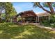 Expansive backyard showcasing a covered patio with a brick fireplace and a lush, green lawn for outdoor activities at 4508 Compass Oaks Dr, Valrico, FL 33596