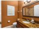 Well-lit bathroom featuring orange walls, a granite countertop, framed mirror, and tiled shower at 4508 Compass Oaks Dr, Valrico, FL 33596