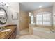 Bright bathroom features a granite vanity, a tiled glass shower, and a soaking tub beneath a shuttered window at 4508 Compass Oaks Dr, Valrico, FL 33596
