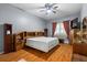 Spacious main bedroom features hardwood floors, a ceiling fan, and a large bed with built-in shelving and decor at 4508 Compass Oaks Dr, Valrico, FL 33596