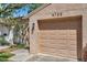 Attached beige garage with a beige door and the house number, complemented by lush greenery and a hint of blue sky at 4733 W Vasconia St, Tampa, FL 33629