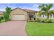 Inviting single-story home with a lush lawn, brick driveway, a two-car garage, and a terracotta-colored tiled roof at 5115 Tobermory Way, Bradenton, FL 34211