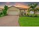 Inviting single-story home with a lush lawn, brick driveway, a two-car garage, and a terracotta-colored tiled roof at 5115 Tobermory Way, Bradenton, FL 34211