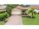 An inviting single-story home with a lush green lawn, brick driveway, a two-car garage, and a terracotta-colored tiled roof at 5115 Tobermory Way, Bradenton, FL 34211