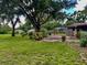 Expansive backyard with mature trees, landscaping, and an outdoor patio area with sheds at 5905 Caroline Dr, Wesley Chapel, FL 33545