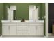 Bathroom featuring double sinks with white cabinets and vanity, and a stylish green accent wall at 7730 Painted Sky Pl, Land O Lakes, FL 34637