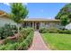 Attractive front entrance with brick pathway, decorative shrubs, and a cozy porch seating area at 8300 37Th N Ave, St Petersburg, FL 33710