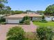 Inviting single-story home with a brick driveway, lush landscaping, and an attached two-car garage at 8300 37Th N Ave, St Petersburg, FL 33710