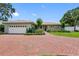 Inviting one-story home with a brick driveway leading to an attached garage and beautifully landscaped front yard at 8300 37Th N Ave, St Petersburg, FL 33710
