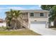 Charming two-story home featuring a two-car garage, front yard with palms, and staircase to the front door at 921 Lynnlea Ln, Tarpon Springs, FL 34689