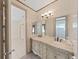 Bathroom with a double vanity, decorative mirror, and access to a glass enclosed shower at 9460 Bearfoot Trl, Weeki Wachee, FL 34613