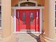 Close-up of a stylish red front door with decorative glass panels and sidelights at 9460 Bearfoot Trl, Weeki Wachee, FL 34613
