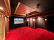 Home theater with a large screen, dark walls, and red carpet at 9460 Bearfoot Trl, Weeki Wachee, FL 34613