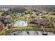 An aerial view shows a community clubhouse and swimming pool nestled beside a lake in a well-treed neighborhood at 9740 Lake Chase Island Way # 9740, Tampa, FL 33626