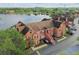 Aerial view of townhouse with orange exterior, brown roof, and a scenic view of a lake and lush greenery at 9740 Lake Chase Island Way # 9740, Tampa, FL 33626