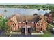Aerial view of orange townhouses with garages, set against a picturesque lakeside backdrop and verdant surroundings at 9740 Lake Chase Island Way # 9740, Tampa, FL 33626