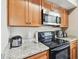 Kitchen showcases wood cabinets, granite counters, and stainless steel microwave at 9740 Lake Chase Island Way # 9740, Tampa, FL 33626