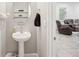 Elegant half bathroom features a pedestal sink, oval mirror, and decorative shelves at 12402 Fairlawn Dr, Riverview, FL 33579