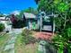 Backyard shed with whimsical mural, swing, and brick patio surrounded by lush plants and flowers at 1345 S Evergreen Ave, Clearwater, FL 33756
