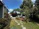 Backyard shed with whimsical mural, swing, and brick patio surrounded by lush plants and flowers at 1345 S Evergreen Ave, Clearwater, FL 33756