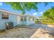 Charming home backyard featuring a small patio, blue exterior, and leafy trees at 1431 Kings Hwy, Clearwater, FL 33755
