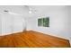 Bright bedroom with hardwood floors, a ceiling fan, and natural light from the window with a view of the neighborhood at 1431 Kings Hwy, Clearwater, FL 33755