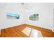 Empty bedroom showing two windows, a ceiling fan, and beautiful hardwood flooring at 1431 Kings Hwy, Clearwater, FL 33755