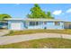 Charming light blue single-story home featuring an attached garage and a white picket fence at 1431 Kings Hwy, Clearwater, FL 33755