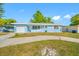 Charming light blue home with attached garage and manicured lawn on a sunny day at 1431 Kings Hwy, Clearwater, FL 33755