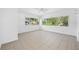 Bright, open living room space with tile flooring, ceiling fan, and a view of the outdoors from several large windows at 1431 Kings Hwy, Clearwater, FL 33755