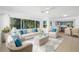 Bright, open living room featuring wicker furniture, a light blue area rug, and large windows overlooking a treed yard at 1431 Kings Hwy, Clearwater, FL 33755