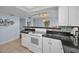 Bright kitchen featuring white cabinets, black countertops, tiled backsplash, and modern appliances at 1451 Gulf Blvd # 207, Clearwater Beach, FL 33767