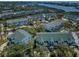 An aerial view displays residential buildings, a pool area, and lush trees in a waterfront community under a clear sky at 14692 Seminole Trl, Seminole, FL 33776