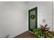 Close-up of a bright green front door with glass panels and a decorative wreath, complemented by potted plants at 14692 Seminole Trl, Seminole, FL 33776