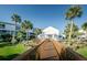 Inviting clubhouse entrance with a charming wooden walkway, tropical palm trees, and manicured landscaping at 14723 Seminole Trl, Seminole, FL 33776