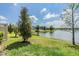 A lush green backyard with a serene lake view surrounded by trees and neighboring houses at 18860 Beautyberry Ct, Lutz, FL 33558