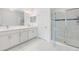 All-white bathroom with double sinks, large mirror, and glass-enclosed shower with white tile at 18860 Beautyberry Ct, Lutz, FL 33558