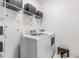 Bright laundry room featuring a white washer and dryer, shelving, and storage baskets at 18860 Beautyberry Ct, Lutz, FL 33558