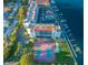 Aerial view showcases condo building with tennis courts, a waterfront pool, and boat docks on a sunny day at 19111 Vista Bay Dr # 304, Indian Shores, FL 33785