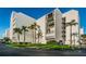 Beautiful exterior of a white building with manicured lawn, shrubs and mature palm trees at 19111 Vista Bay Dr # 304, Indian Shores, FL 33785