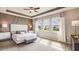 Bright main bedroom with tray ceiling, decorative accent wall, and three large windows providing natural light at 19695 Gladeview Way, Land O Lakes, FL 34638