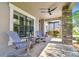Inviting front porch with rocking chairs, stone columns, and a ceiling fan at 21627 Pearl Crescent Ct, Land O Lakes, FL 34637