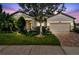 Charming home with well-manicured lawn, mature landscaping, and a brick paver driveway at dusk at 21627 Pearl Crescent Ct, Land O Lakes, FL 34637