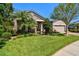 Beautiful home with lush green lawn, mature trees, manicured landscaping, and stone accents at 21627 Pearl Crescent Ct, Land O Lakes, FL 34637