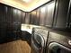 This laundry room offers dark cabinets, countertop space, and stainless steel washer and dryer units at 21627 Pearl Crescent Ct, Land O Lakes, FL 34637