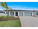 Beautiful single-story home with a two-car garage, brick driveway and a manicured lawn and tropical landscaping at 2731 Winding Creek Trl, North Port, FL 34289
