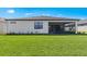 Rear exterior view of the home featuring a well-manicured lawn and screened-in lanai at 2731 Winding Creek Trl, North Port, FL 34289